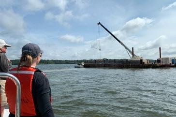 Laura Brown (left), owner of Fox Point Oysters, and Ray Grizzle, a UNH professor of biological sciences, watch as a crane operated by Riverside & 皮克林海洋工程公司在南泥岛珊瑚礁修复地点存放牡蛎壳.
